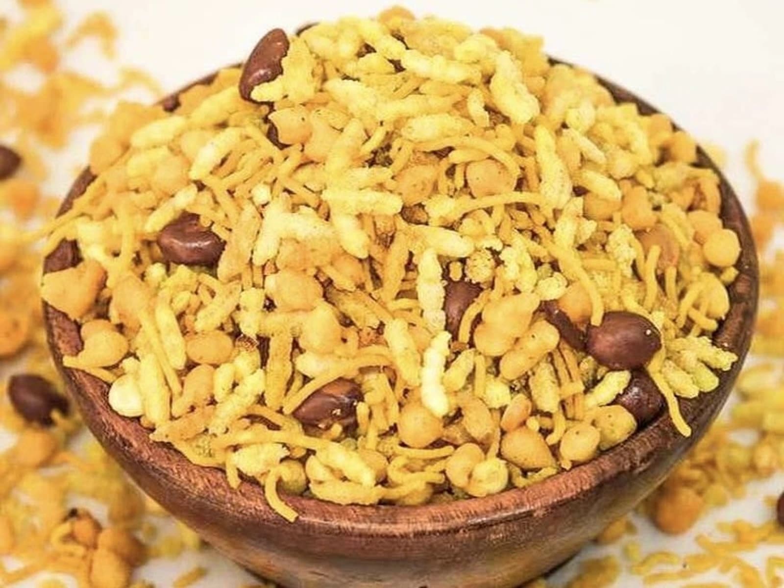 Wooden bowl of atukula mixture with crunchy flakes, sev, boondi, and peanuts